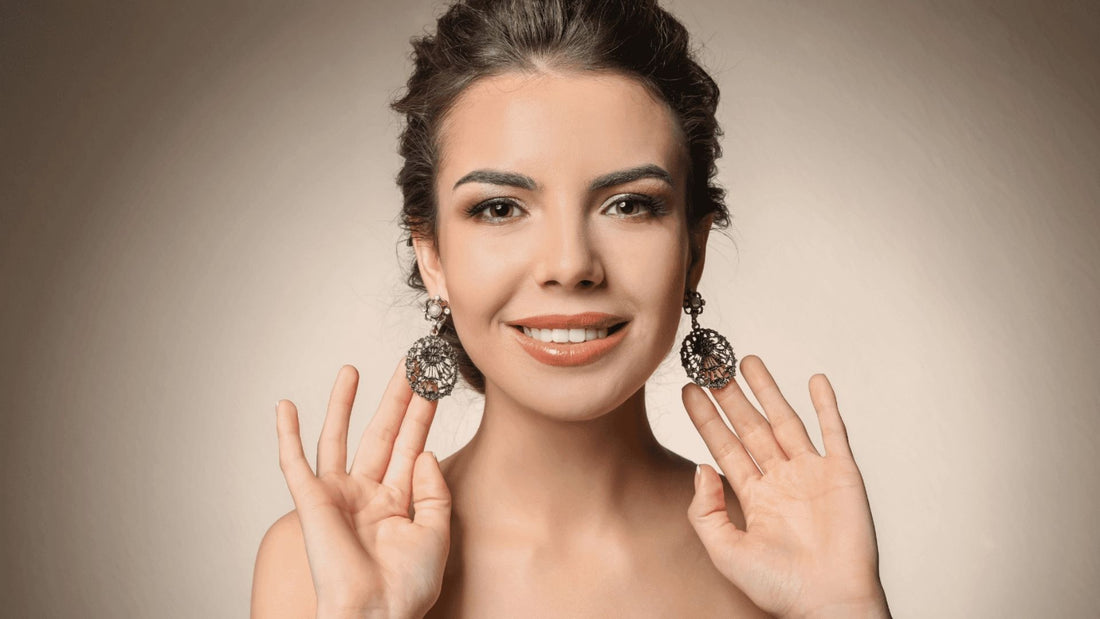 Woman modelling sparkling statement earrings and delicate jewellery against a neutral backdrop