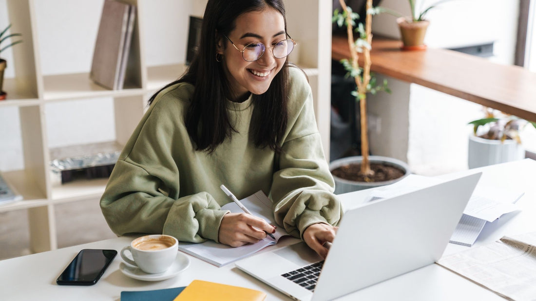 Woman reviewing jewellery designs and notes at a desk before buying an engagement ring online