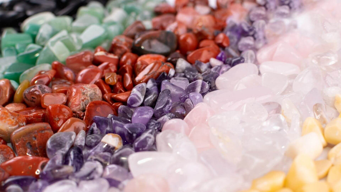 Colourful assortment of polished crystals and gemstones arranged in a graduated spectrum