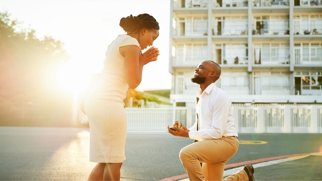 Man kneeling to propose to a woman in warm sunlight, evoking the enduring romance of a diamond engagement ring