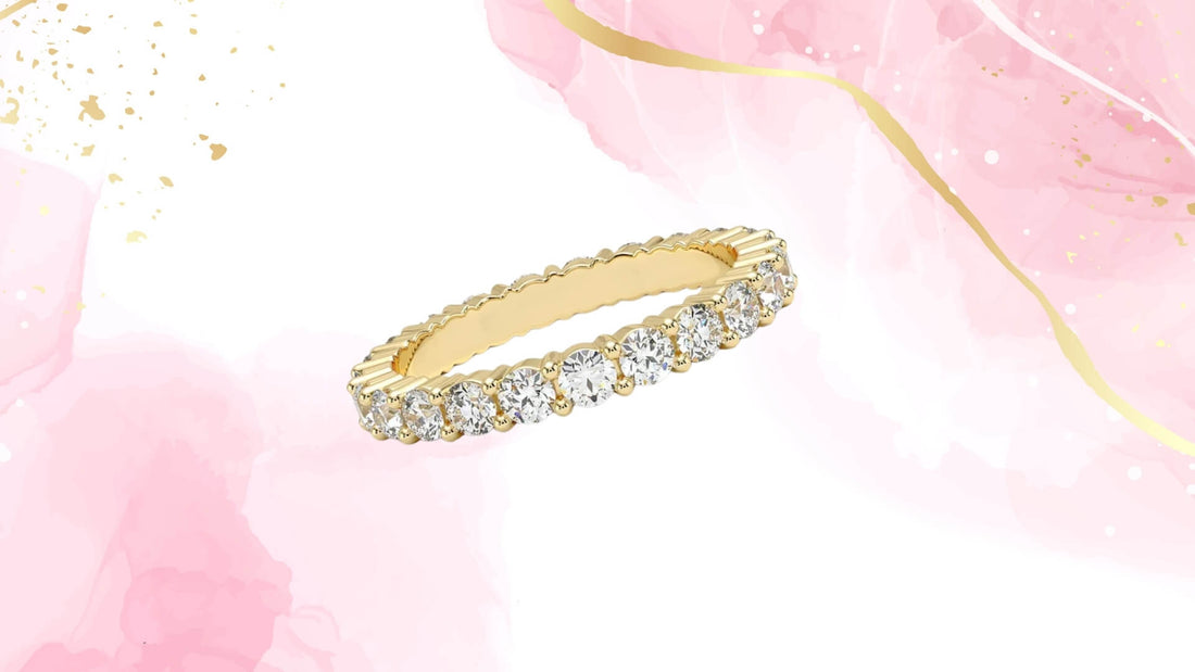 Slim gold diamond eternity band displayed on a blush pink and white background