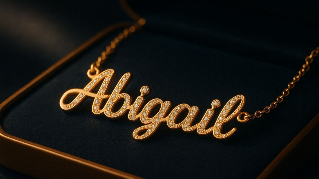 Gold personalized name necklace spelling Abigail on a fine chain against a dark background