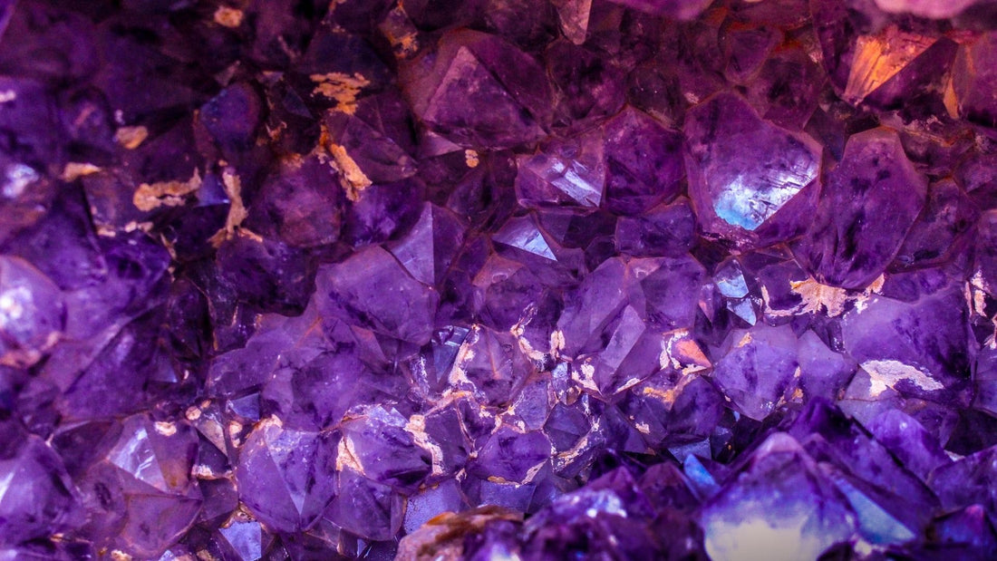 Cluster of purple amethyst crystals sparkling against a violet background