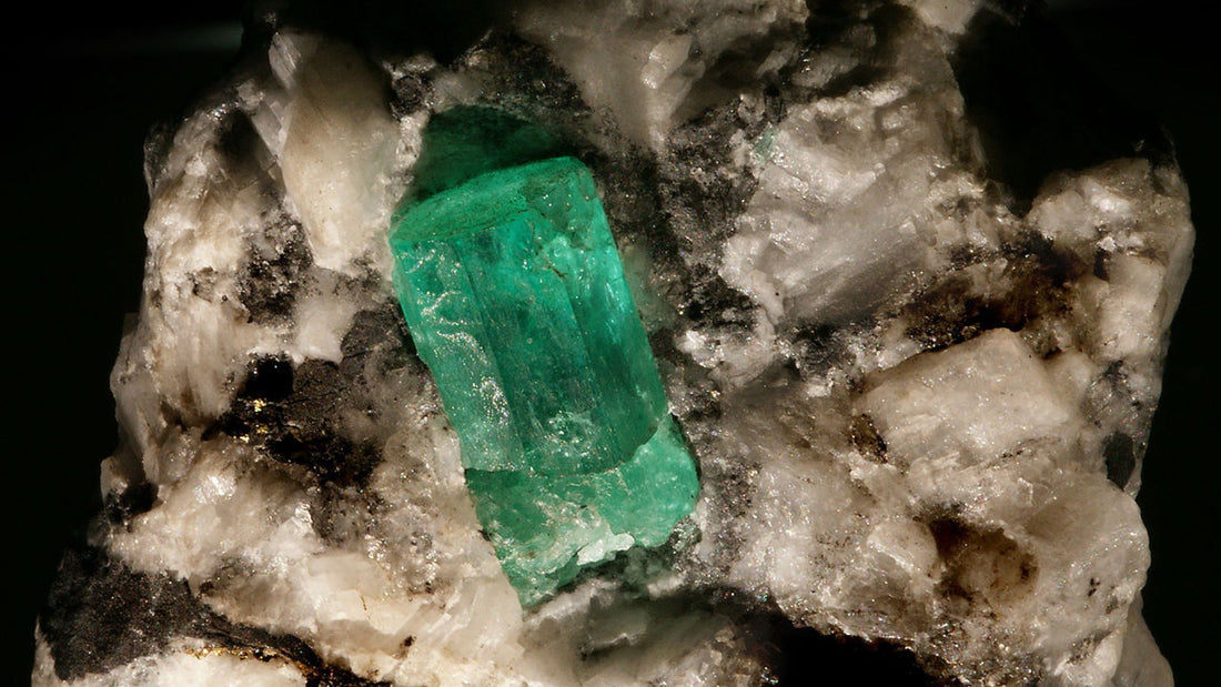 Natural green emerald embedded in its rough mineral host rock before gemstone cutting