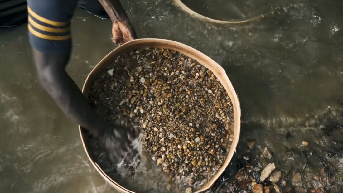 Rough natural diamond stones and a sieve on a dark work surface, illustrating traditional diamond diving and recovery