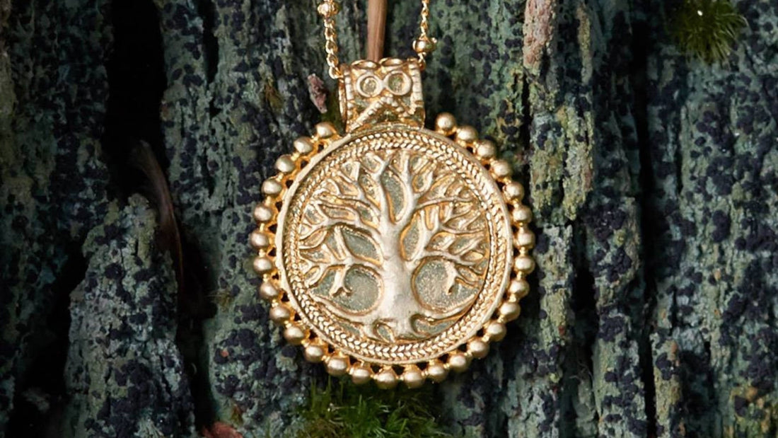 Round gold Tree of Life pendant against weathered tree bark, with intricately branching motifs