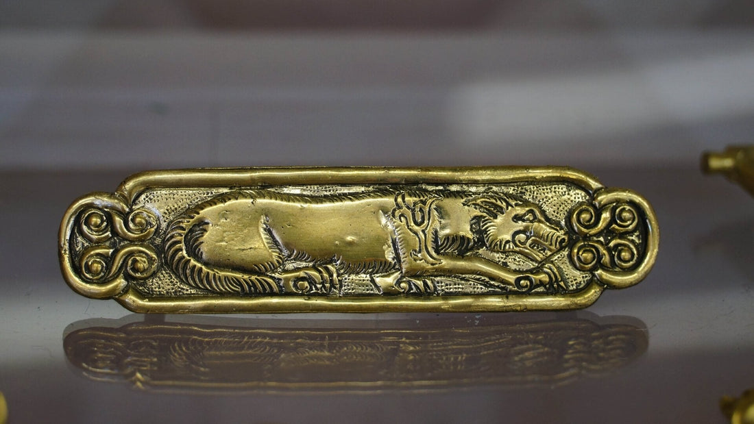 Antique gold jewellery decorated with a wolf motif on a weathered stone surface