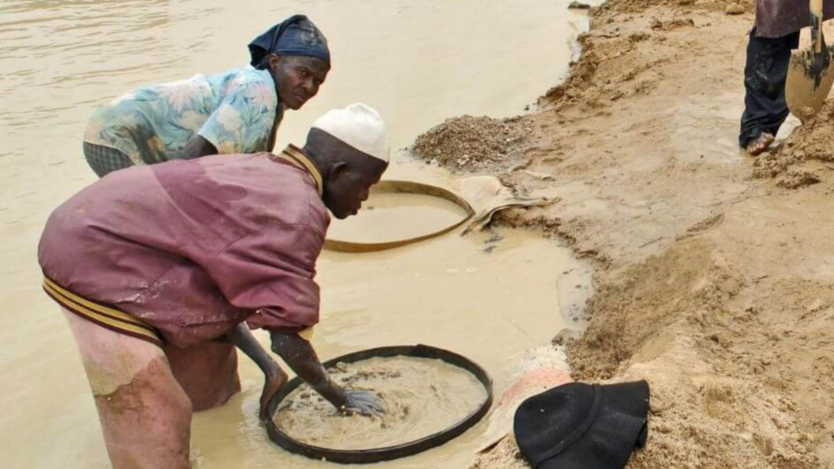 Person panning for mineral stones outdoors in an alluvial mining setting