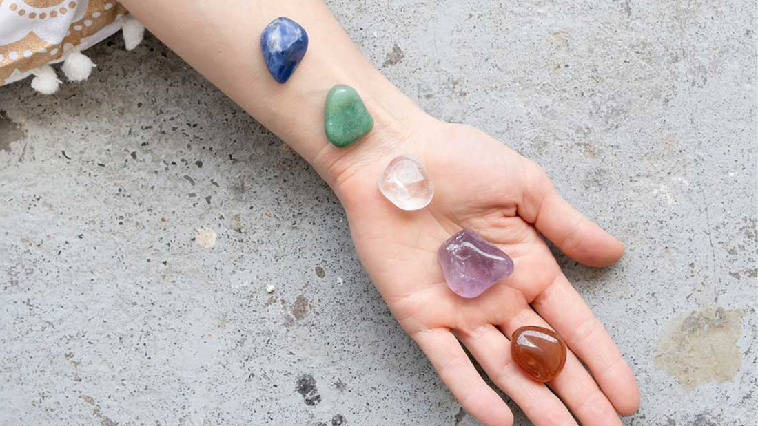 Hand holding polished crystals and gemstones, illustrating their use in traditional gem therapy