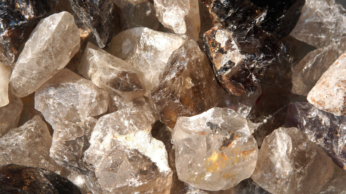 Natural smoky quartz crystal points and brown translucent mineral specimens grouped on a neutral surface