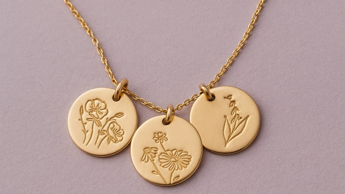 Three gold birth flower pendant necklaces engraved with botanical motifs against a soft lavender background
