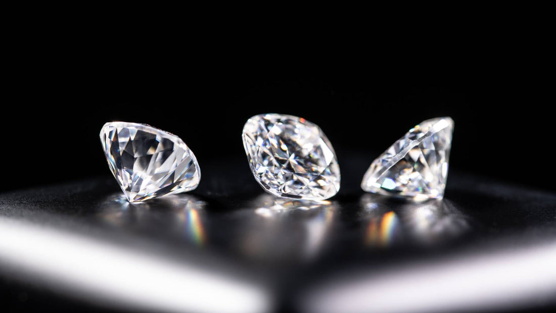 Three colourless diamonds showing white brilliance and colourful light reflections