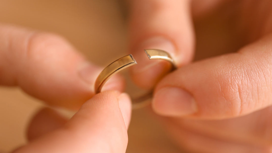Hands repairing a broken piece of jewellery beside a box of keepsakes