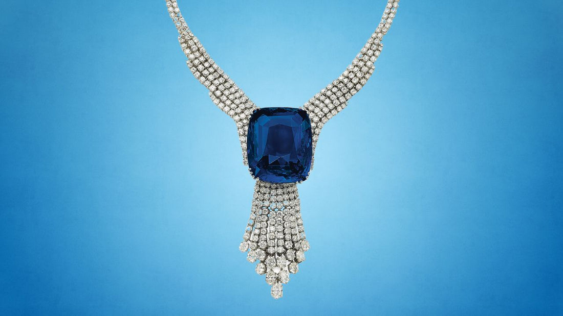 Royal blue sapphire pendant framed by white diamonds on a pale blue background