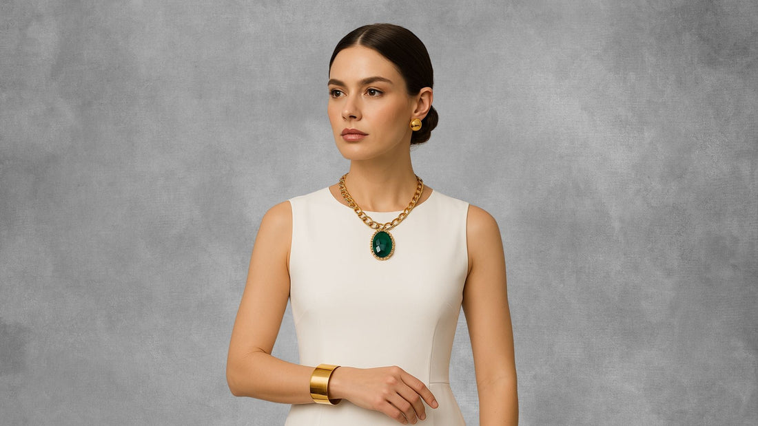 Woman in a white monochrome outfit wearing an emerald-green pendant necklace and matching earrings