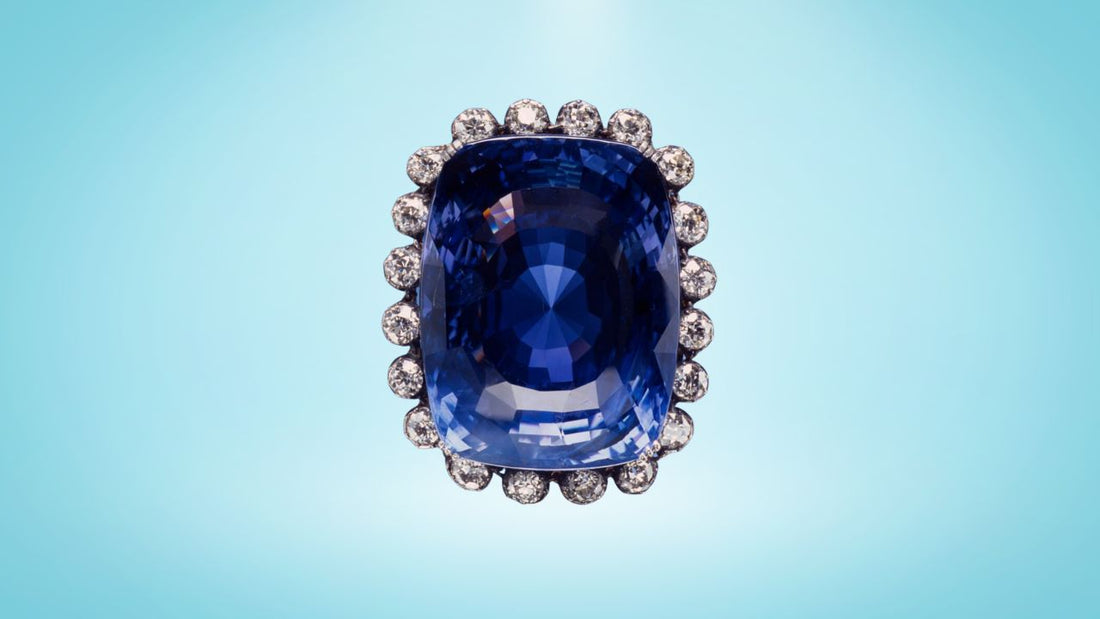 Deep blue oval Logan Sapphire surrounded by brilliant diamonds against a pale blue background