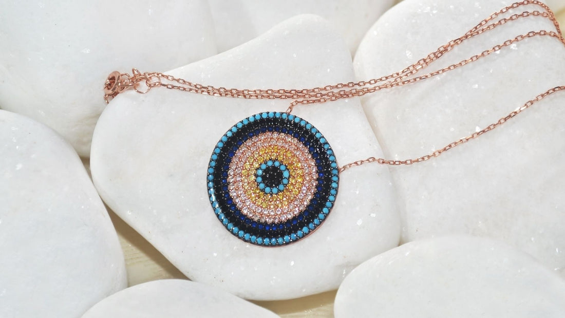 Handmade protective evil eye pendant on a delicate chain against white fabric